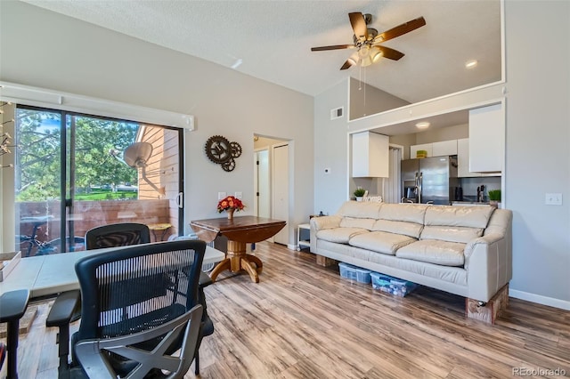 living room with ceiling fan, high vaulted ceiling, a textured ceiling, and wood-type flooring