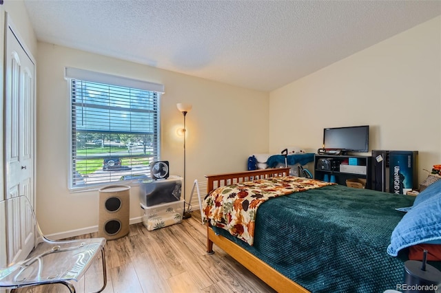 bedroom with a textured ceiling, a closet, and light wood-type flooring