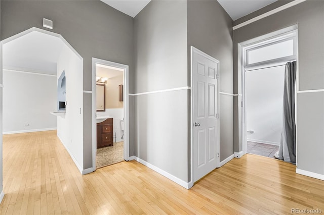 corridor with light wood-style flooring and baseboards