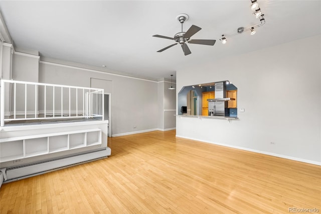 spare room with baseboards, a ceiling fan, wood finished floors, rail lighting, and a baseboard heating unit