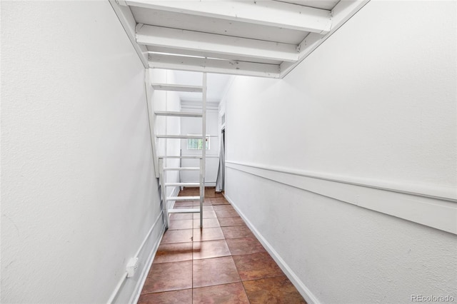 hall featuring dark tile patterned floors and baseboards