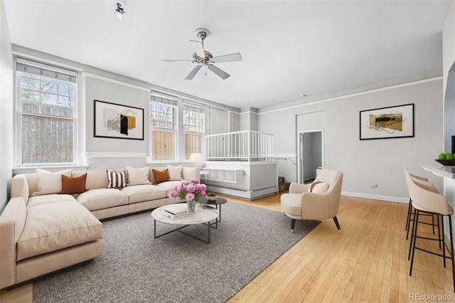 living room with hardwood / wood-style flooring, ceiling fan, and ornamental molding