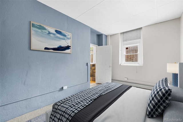 bedroom featuring a baseboard radiator and a textured wall