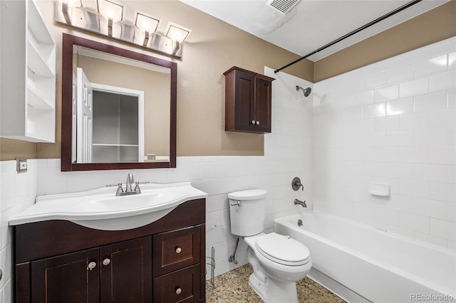 full bath with visible vents, toilet, speckled floor, vanity, and tile walls