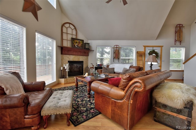 living area with ceiling fan, high vaulted ceiling, light wood finished floors, and a premium fireplace