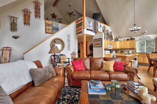 living room with high vaulted ceiling, beam ceiling, light wood-style flooring, and ceiling fan with notable chandelier