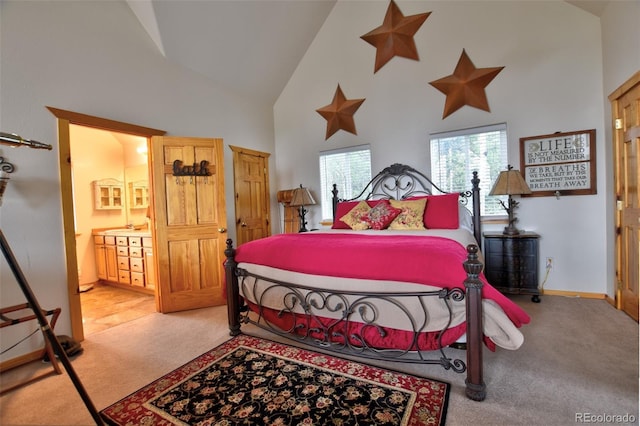 bedroom featuring light carpet, high vaulted ceiling, baseboards, and ensuite bathroom