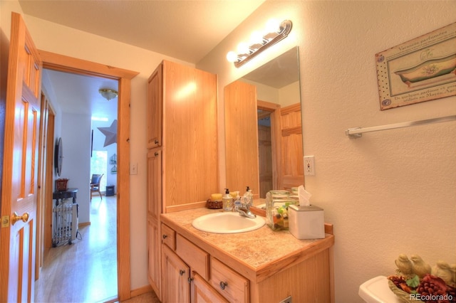 half bathroom with toilet, a textured wall, and vanity