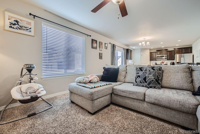 carpeted living room with ceiling fan with notable chandelier