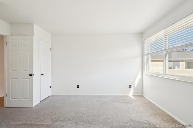 carpeted empty room featuring baseboards