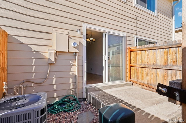 view of exterior entry with central AC unit and fence