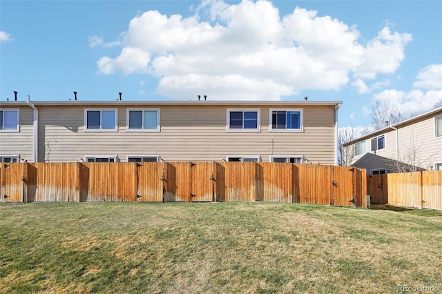 back of house featuring a yard, a gate, and a fenced backyard
