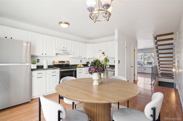 8975 Field St Unit 39, Broomfield, CO 80021 - kitchen featuring stainless steel appliances, under cabinet range hood, dark countertops, a chandelier, and white cabinetry