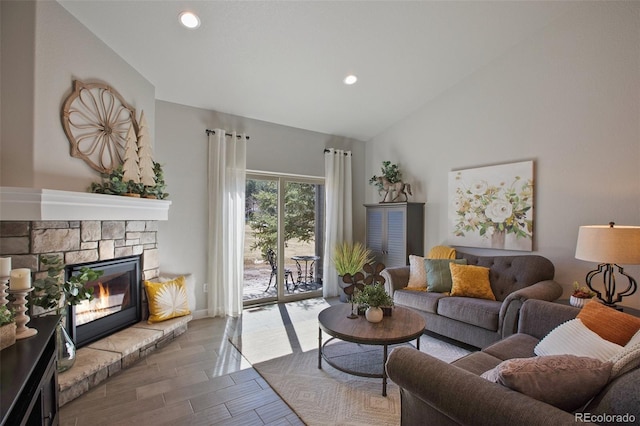 living room featuring wood-type flooring, lofted ceiling, and a stone fireplace