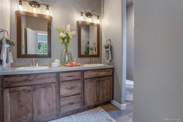 bathroom with double sink, toilet, oversized vanity, and tile flooring