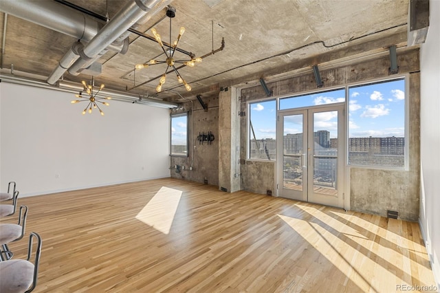 2020 Arapahoe St Unit 970, Denver, CO 80205 - unfurnished living room featuring a chandelier, wood finished floors, a view of city, and french doors