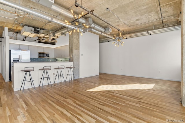 2020 Arapahoe St Unit 970, Denver, CO 80205 - kitchen featuring a chandelier, stainless steel appliances, light wood finished floors, and a high ceiling