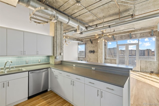 2020 Arapahoe St Unit 970, Denver, CO 80205 - kitchen with stainless steel dishwasher, a sink, light wood finished floors, a peninsula, and backsplash