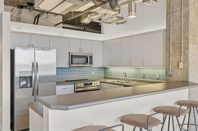 2020 Arapahoe St Unit 970, Denver, CO 80205 - kitchen featuring appliances with stainless steel finishes, a sink, a peninsula, a kitchen breakfast bar, and backsplash
