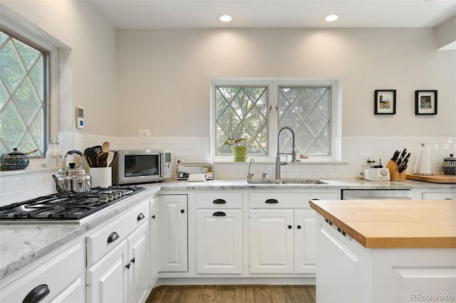 36 Lake Ave, Colorado Springs, CO 80906 - kitchen with stainless steel appliances, a sink, wood finished floors, backsplash, and white cabinets