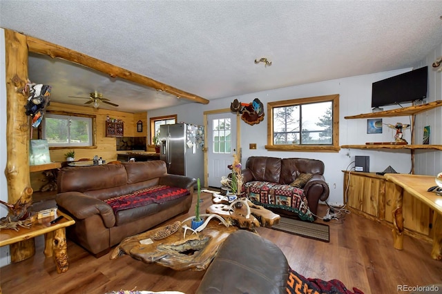 living room with beam ceiling, a healthy amount of sunlight, ceiling fan, and hardwood / wood-style floors