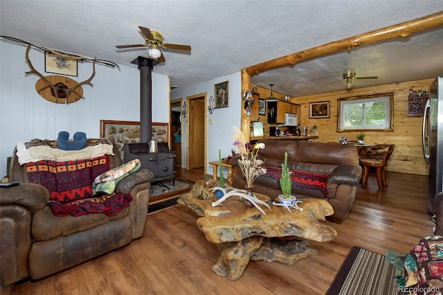 living room featuring hardwood / wood-style flooring, a wood stove, a textured ceiling, and ceiling fan