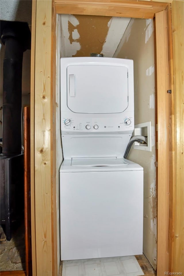 clothes washing area featuring stacked washer and clothes dryer and light tile patterned floors