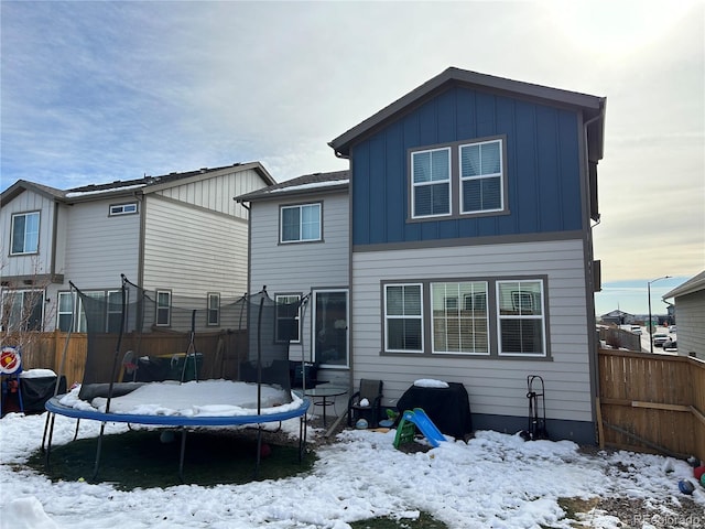 snow covered house featuring a trampoline