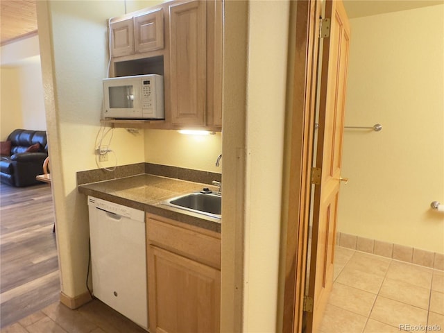 kitchen featuring sink, white appliances, light brown cabinetry, and light tile patterned floors