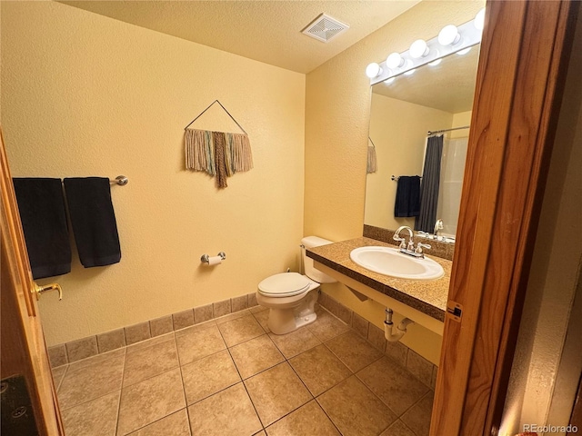 bathroom with toilet, walk in shower, tile patterned floors, a textured ceiling, and sink