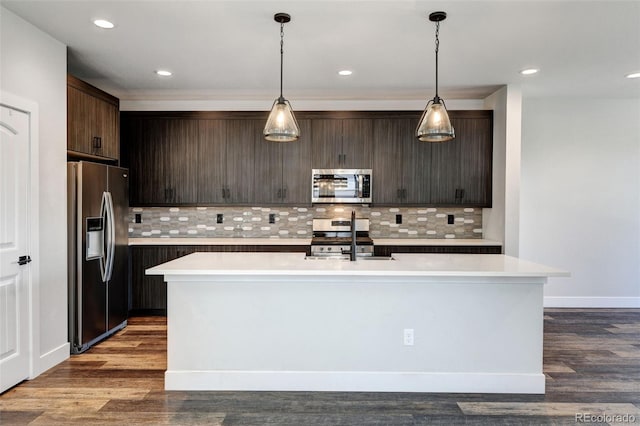 kitchen featuring a center island with sink, stainless steel appliances, dark brown cabinetry, and decorative backsplash