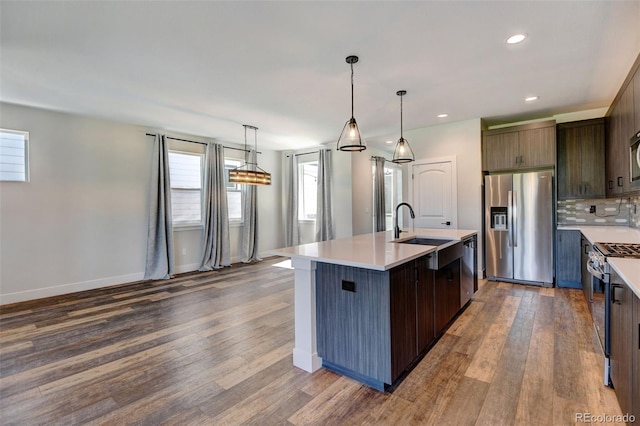 kitchen with dark brown cabinets, stainless steel appliances, sink, dark hardwood / wood-style floors, and a center island with sink