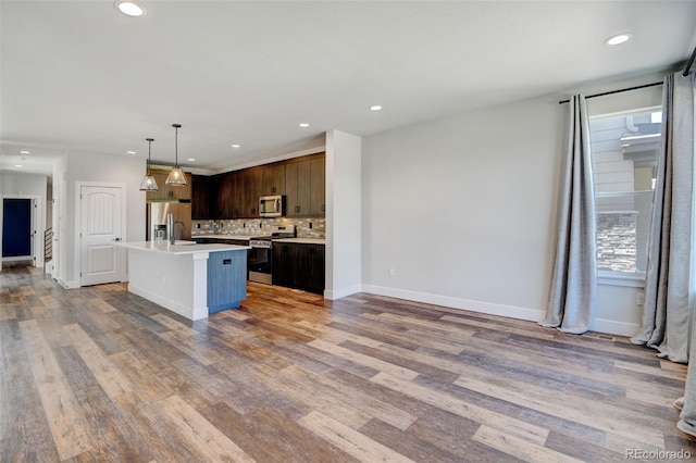 kitchen featuring light hardwood / wood-style flooring, dark brown cabinets, decorative light fixtures, and stainless steel appliances