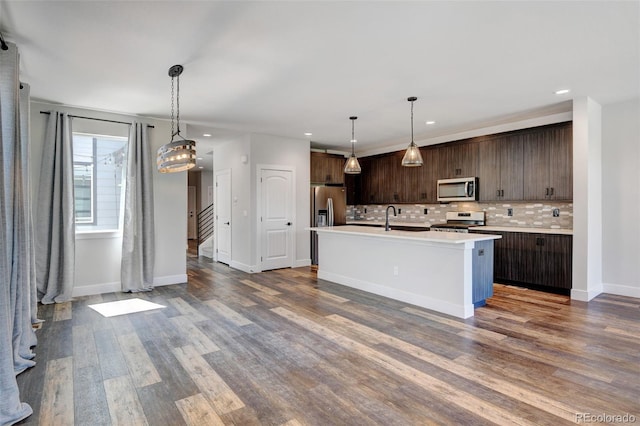 kitchen with a center island with sink, stainless steel appliances, hardwood / wood-style floors, and dark brown cabinetry