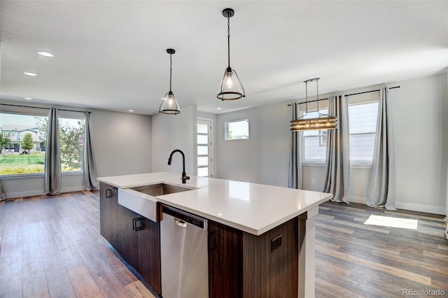 kitchen with a kitchen island with sink, dishwasher, sink, hardwood / wood-style flooring, and dark brown cabinetry