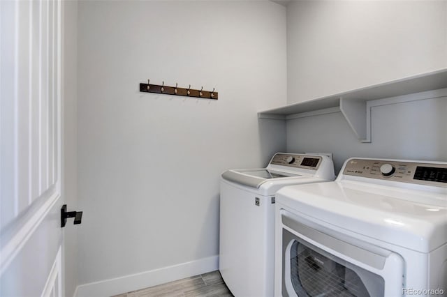 washroom with light wood-type flooring and washing machine and clothes dryer