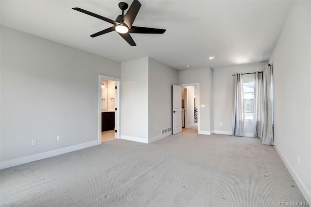 unfurnished bedroom featuring light colored carpet, ensuite bathroom, and ceiling fan