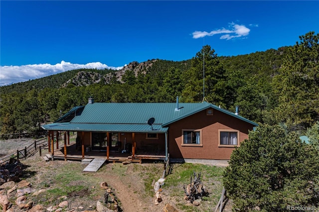 701/700 Bella Vista Ln, Cotopaxi, CO 81223 - view of front of house featuring a wooded view, a mountain view, metal roof, covered porch, and a chimney