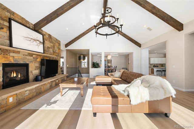 living room featuring a stone fireplace, beamed ceiling, light hardwood / wood-style floors, and high vaulted ceiling