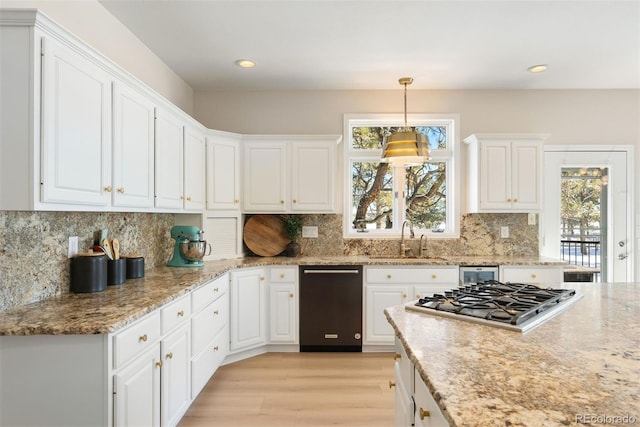 kitchen with light wood-type flooring, sink, decorative light fixtures, white cabinets, and stainless steel gas stovetop