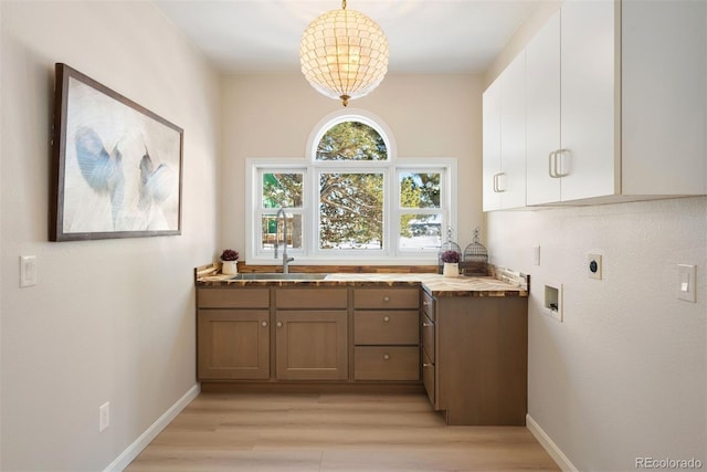 kitchen featuring pendant lighting, light wood-type flooring, white cabinetry, and sink