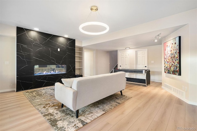 living room with a high end fireplace and light hardwood / wood-style flooring