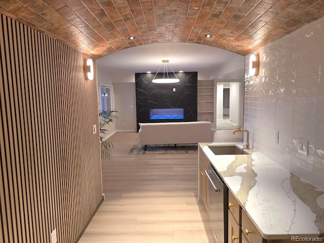 interior space with lofted ceiling, sink, tile walls, light hardwood / wood-style floors, and brick ceiling