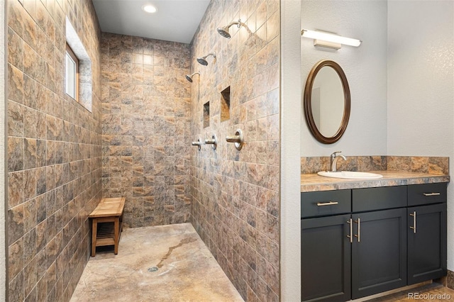 bathroom with tiled shower and vanity