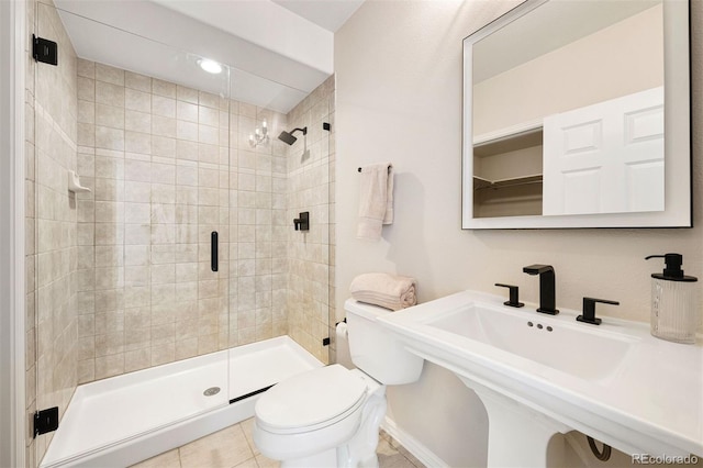 bathroom featuring tile patterned flooring, toilet, walk in shower, and sink