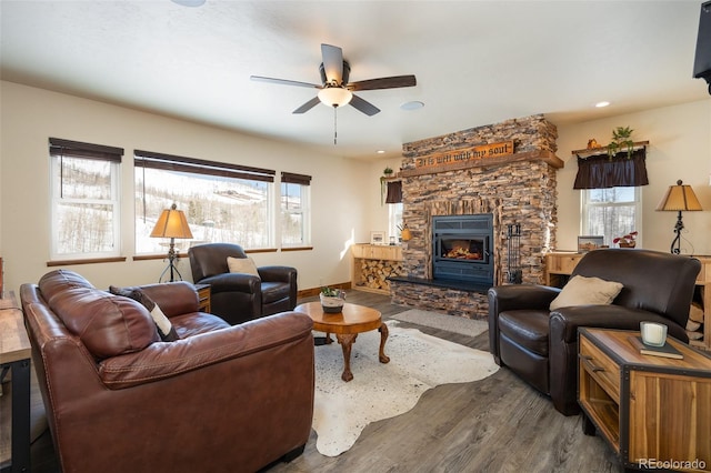 living room with ceiling fan, a stone fireplace, recessed lighting, wood finished floors, and baseboards