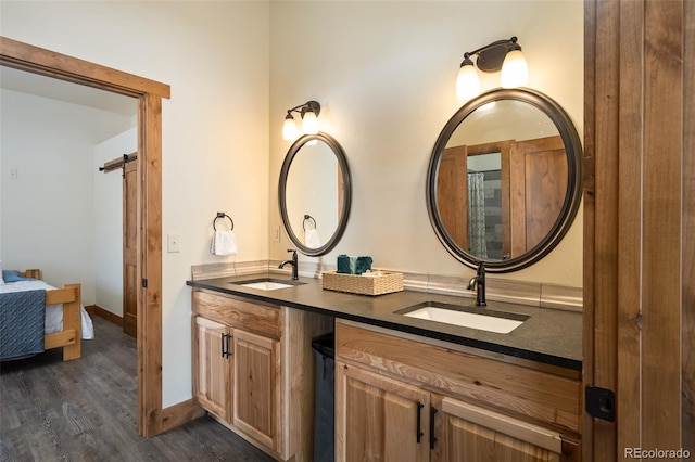 full bath with double vanity, wood finished floors, a sink, and baseboards