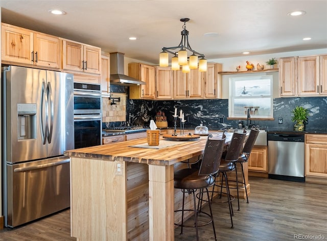 kitchen with stainless steel appliances, wall chimney range hood, and light brown cabinetry