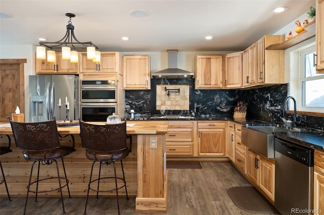 kitchen with appliances with stainless steel finishes, dark wood finished floors, wall chimney range hood, and light brown cabinetry