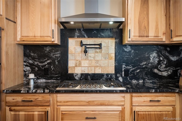 kitchen featuring tasteful backsplash, dark countertops, stainless steel gas cooktop, and wall chimney range hood